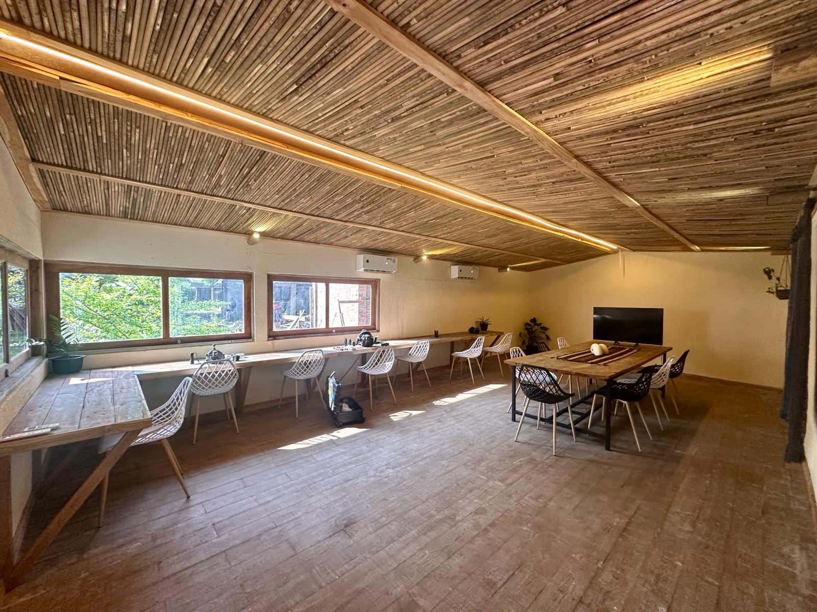 The camera room — long bench workstations under a bamboo ceiling, large monitor at the back