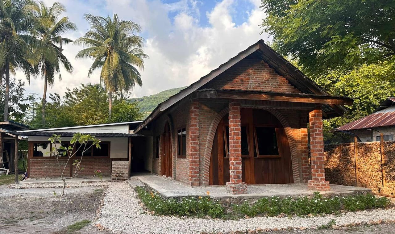 The dive center building — brick walls, wooden arches, a sheltered porch under palm trees