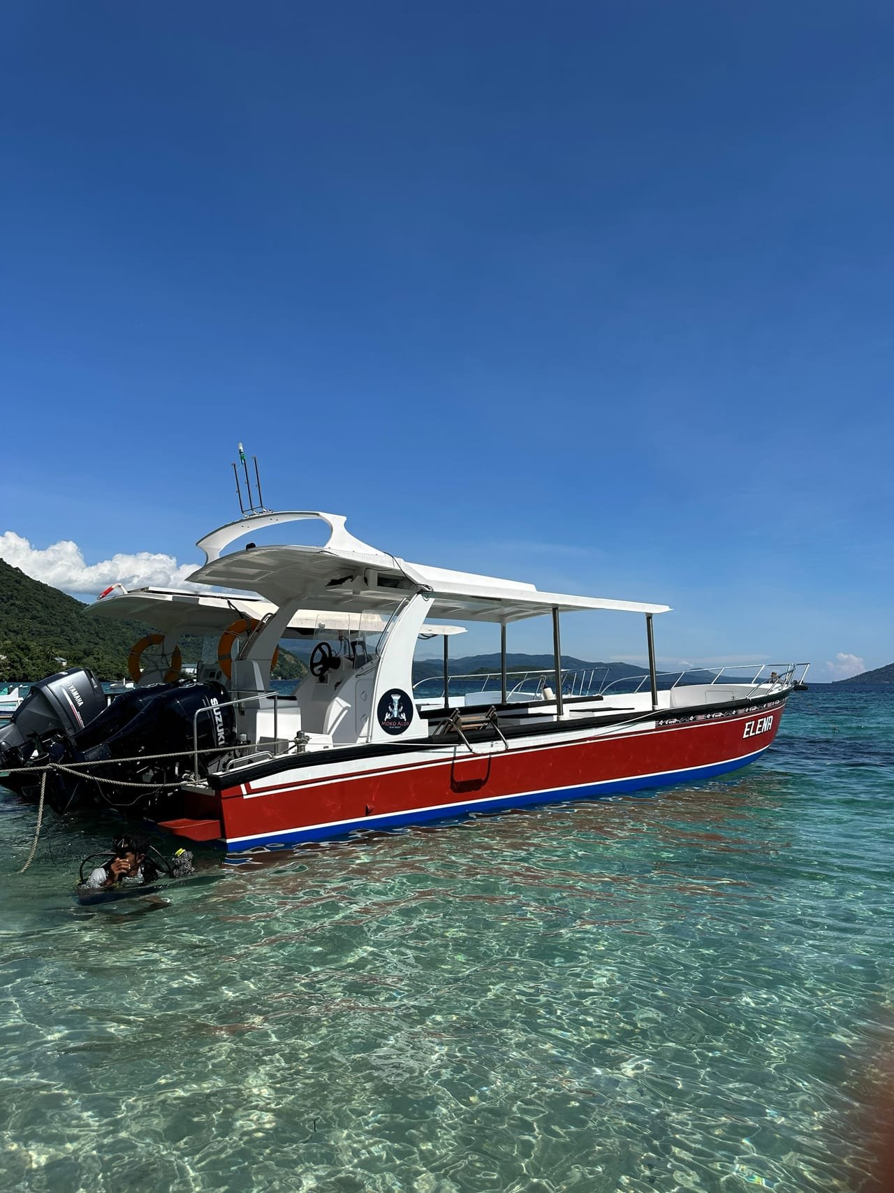 Speedboat Elena moored in shallow turquoise water with mountainous backdrop