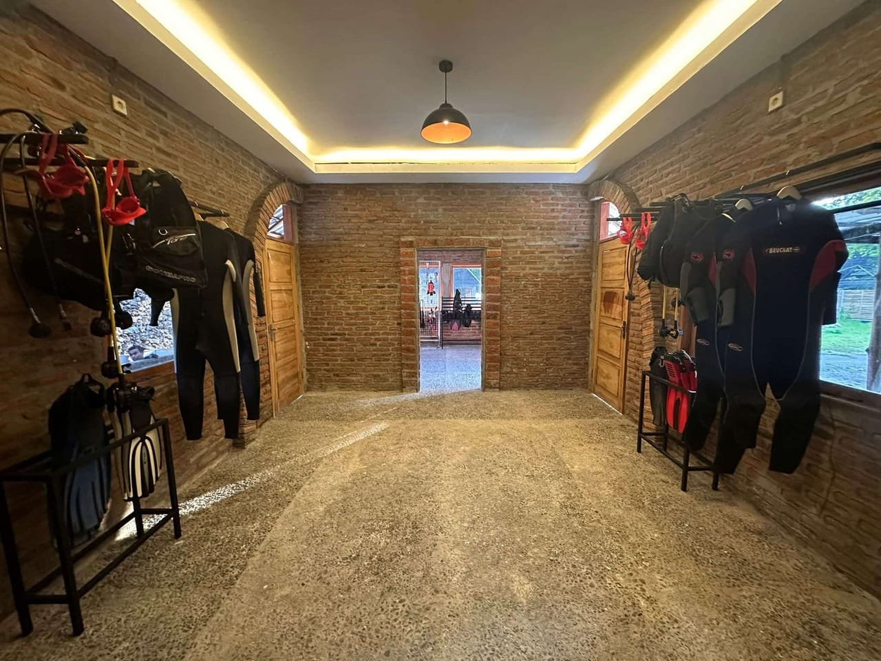 The rental room — wetsuits and BCDs hanging from racks along exposed brick walls